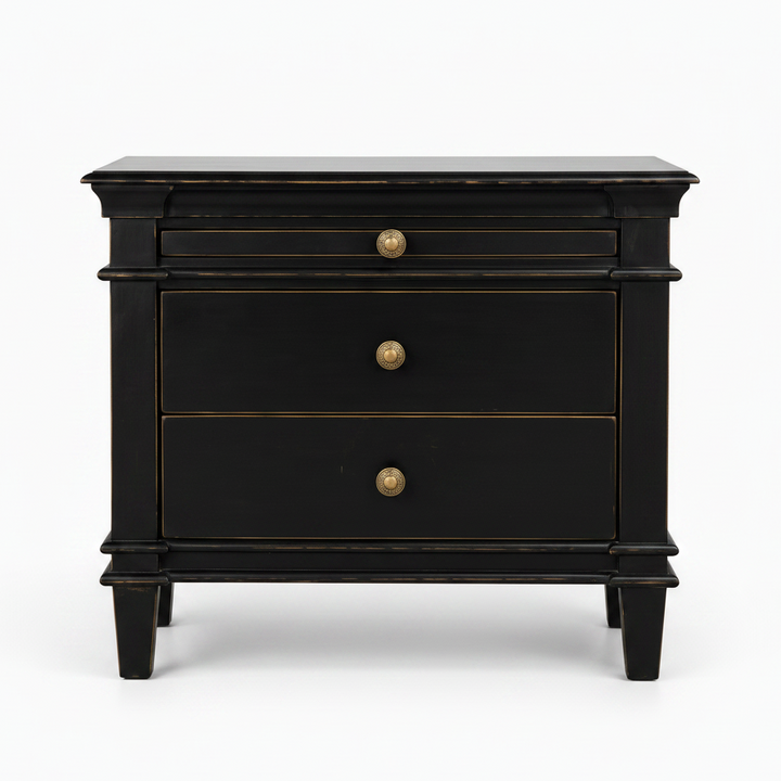 A black three-drawer nightstand with brass-finished round knobs and subtle gold-toned trim, photographed against a clean white background.