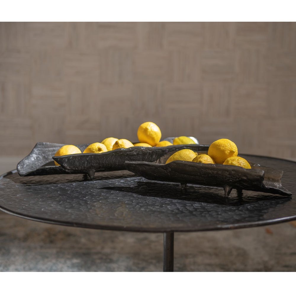 Two elegant black bowls filled with bright yellow lemons, placed on a textured black table.