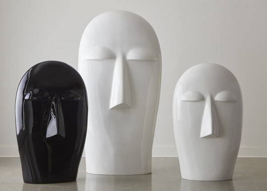 Three abstract face-shaped sculptures in black, white on a light background