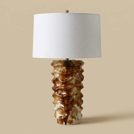 Table lamp with a textured brown base and white shade on a beige background