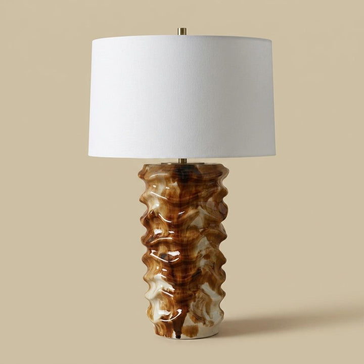 Table lamp with a textured brown base and white shade on a beige background