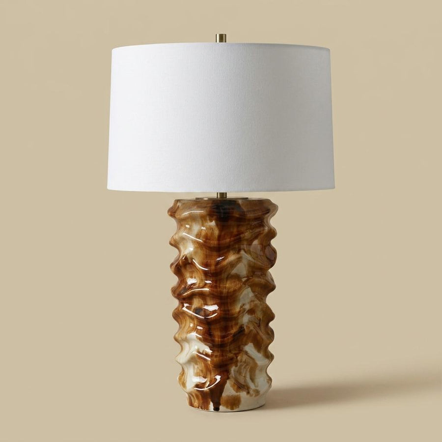 Table lamp with a textured brown base and white shade on a beige background