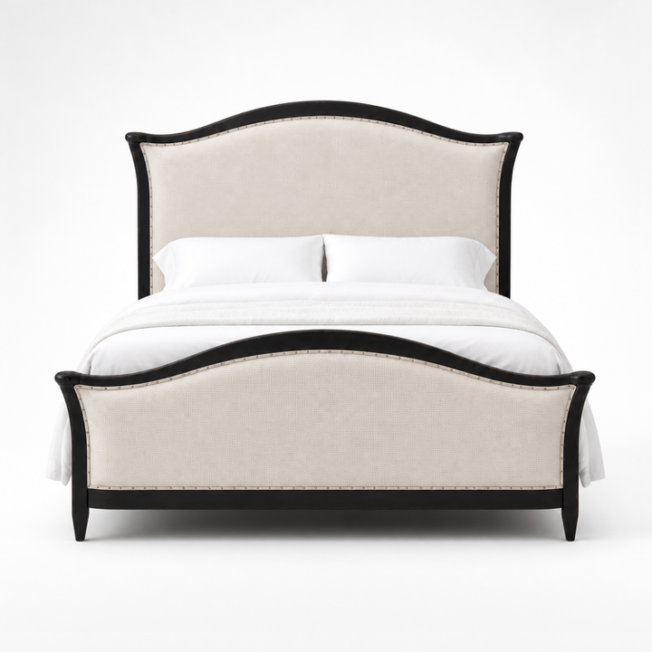 A classic upholstered bed with a curved headboard and matching footboard, featuring a light beige fabric cover and a black wood frame, styled with white bedding and pillows against a plain background.