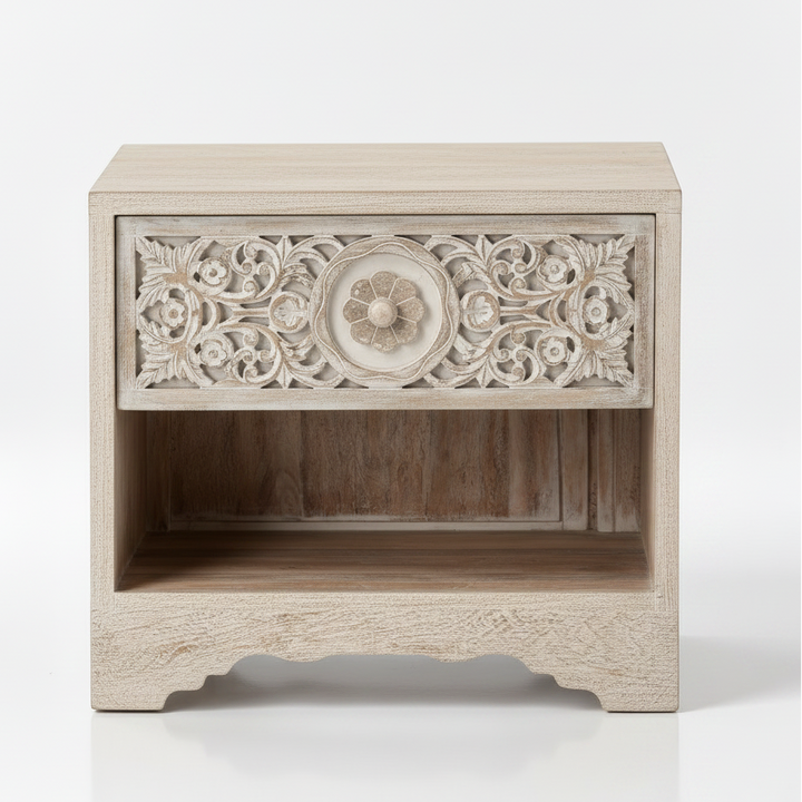 Wooden nightstand, whitewashed finish, intricate floral carvings on drawer front, central circular motif, open shelf below, scalloped base, rustic vintage style