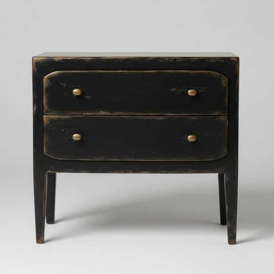 A distressed black two-drawer nightstand with brass knobs, photographed against a neutral light gray background.