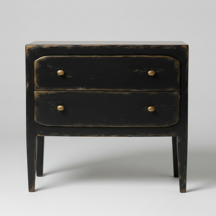A distressed black two-drawer nightstand with brass knobs, photographed against a neutral light gray background.