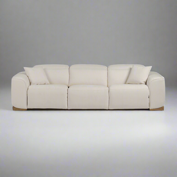 A modern beige fabric sofa featuring plush cushions and two decorative pillows, set against a neutral gray background.