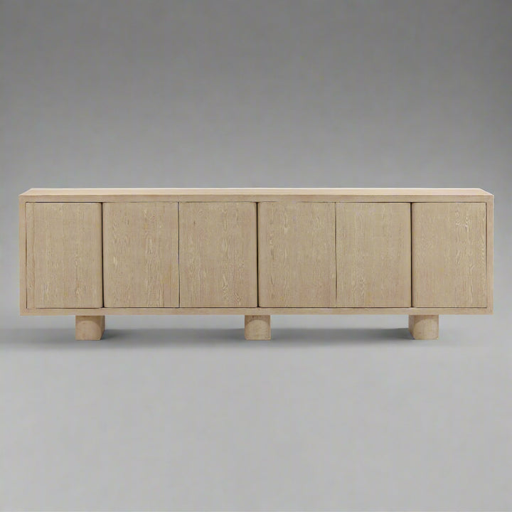 Light-colored wooden sideboard with four flat doors and rounded feet, showcasing a minimalist design.