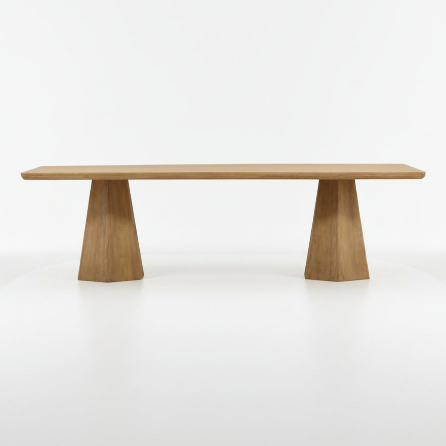 A modern wooden dining table with a rectangular light oak tabletop and two tapered geometric pedestal legs, shown against a plain white background.