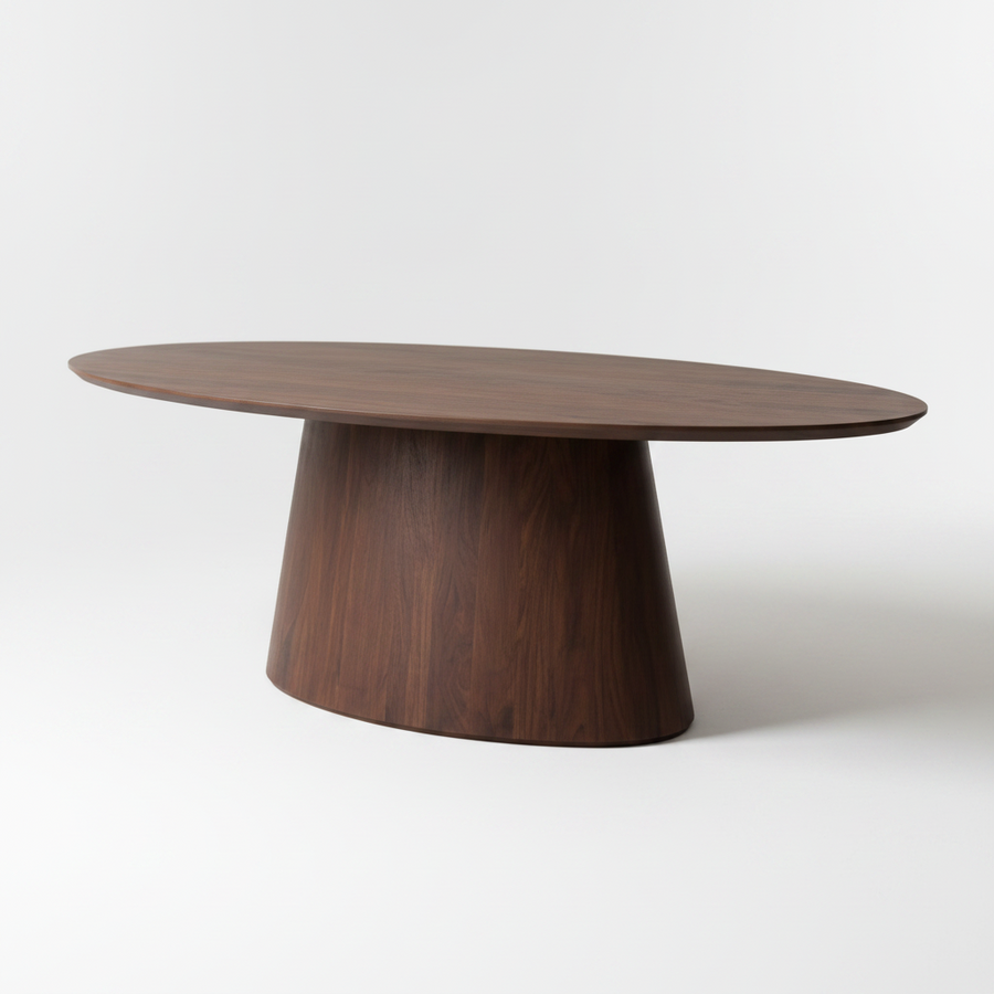 An oval wooden dining table with a dark walnut finish, featuring a tapered pedestal base, photographed on a seamless light gray studio background.