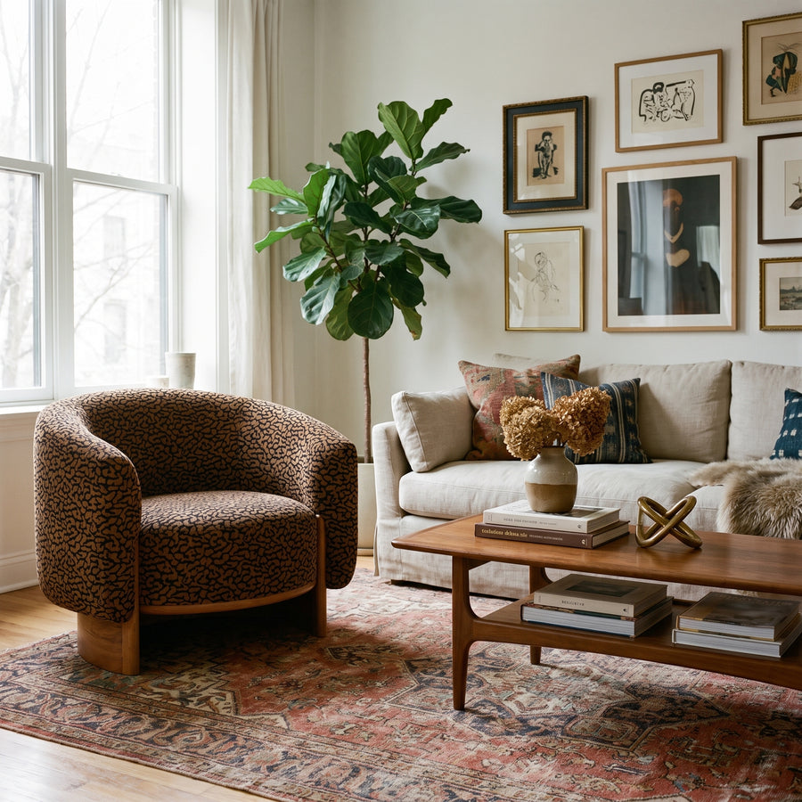 Cozy living room with a leopard print armchair, neutral sofa, fiddle leaf fig, gallery wall, and vintage-style area rug.