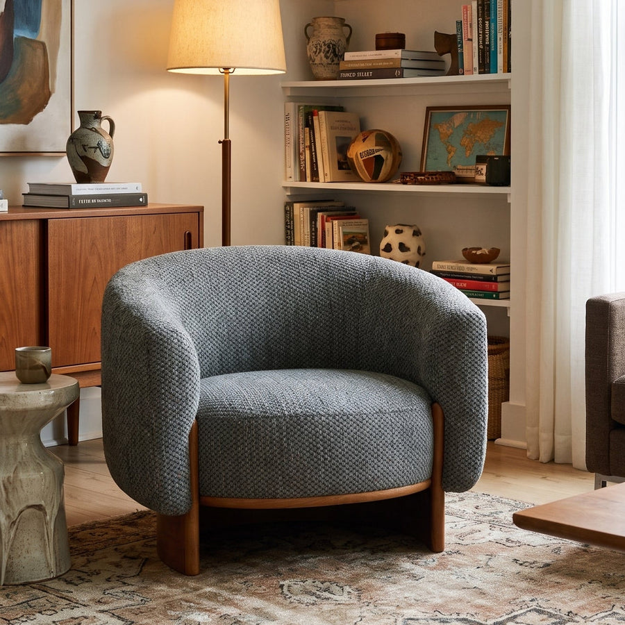 Modern living room with a textured gray armchair, mid-century wood sideboard, abstract art, and a cozy bookshelf.