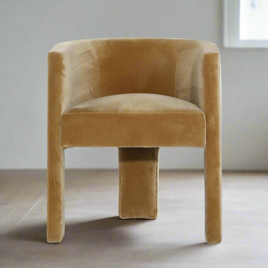 Brown velvet chair on a light wooden floor with a white wall background
