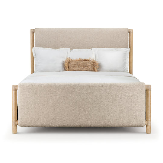 Front view of a bed with a light wood frame and beige upholstered headboard and footboard. Dressed with white bedding and features a single textured brown accent pillow.