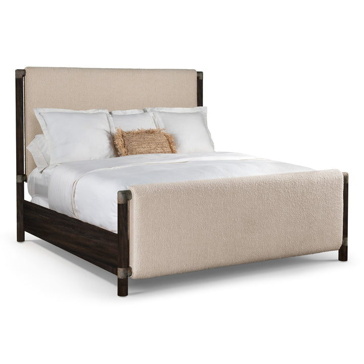 Modern upholstered bed with a soft beige headboard and footboard, featuring dark wooden frame and layered white bedding with decorative pillow.