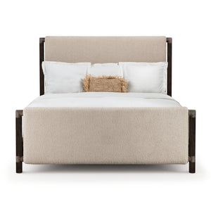 Modern upholstered bed with a soft beige headboard and footboard, featuring dark wooden frame and layered white bedding with decorative pillow.