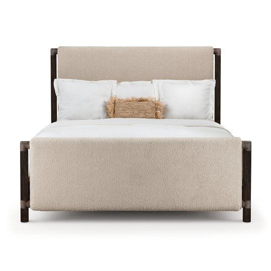 Modern upholstered bed with a soft beige headboard and footboard, featuring dark wooden frame and layered white bedding with decorative pillow.