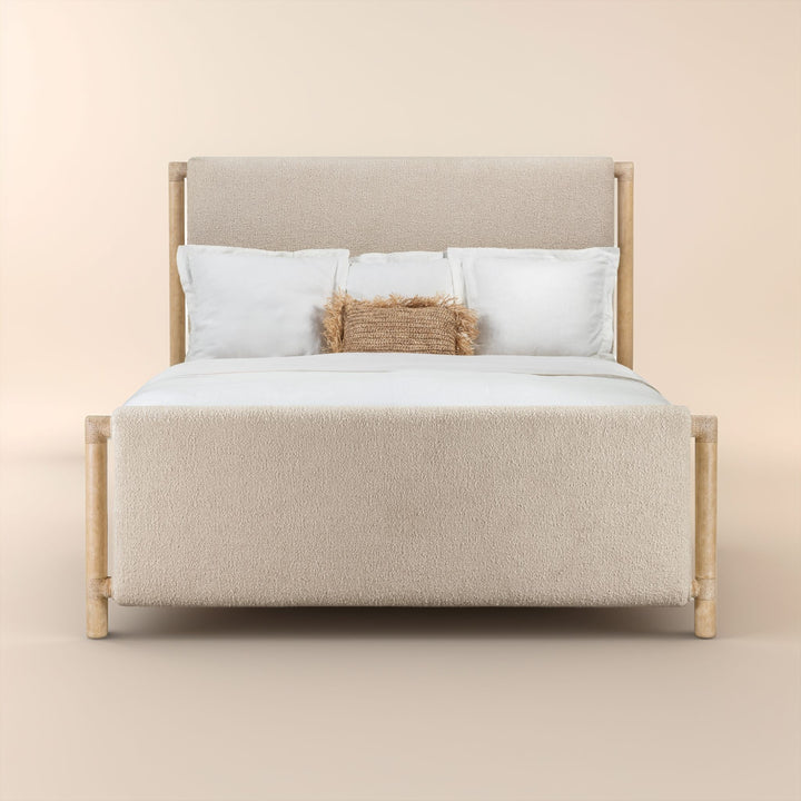 Front view of a bed with a light wood frame and beige upholstered headboard and footboard. Dressed with white bedding and features a single textured brown accent pillow.