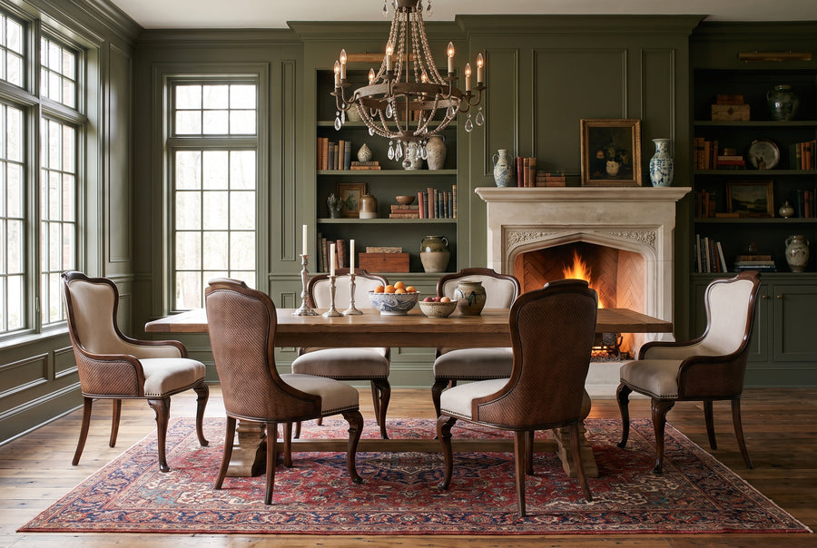 Elegant dining room with dark green paneled walls, a stone fireplace, wooden table, and traditional vintage-style decor.