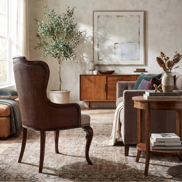 Elegant living room with a vintage wingback chair, mid-century sideboard, plush sofa, and patterned rug in a warm, neutral palette.