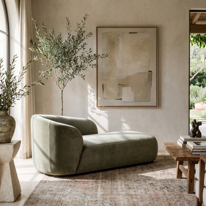 Modern Mediterranean living room with a sage green chaise lounge, olive tree, abstract art, and a vintage-style area rug.