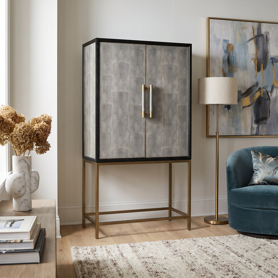 Mako Shagreen Tall Bar Cabinet in a modern living room, featuring a textured grey finish and elegant gold metal base.