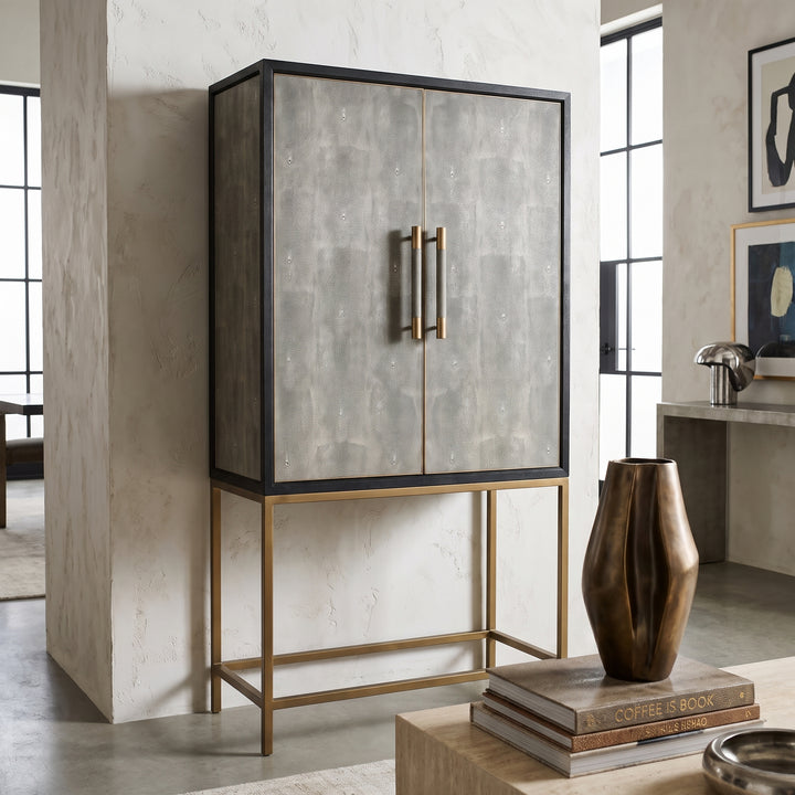 Modern living room featuring a tall, grey shagreen bar cabinet with gold metal legs and brass hardware, styled with decor.