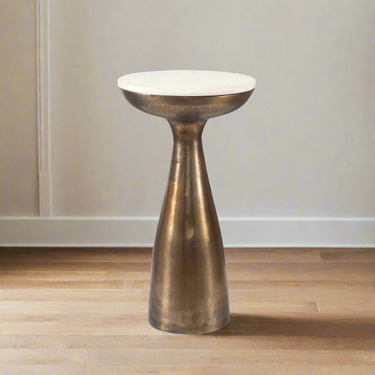 Bronze-colored pedestal with white top on a wooden floor against a plain wall